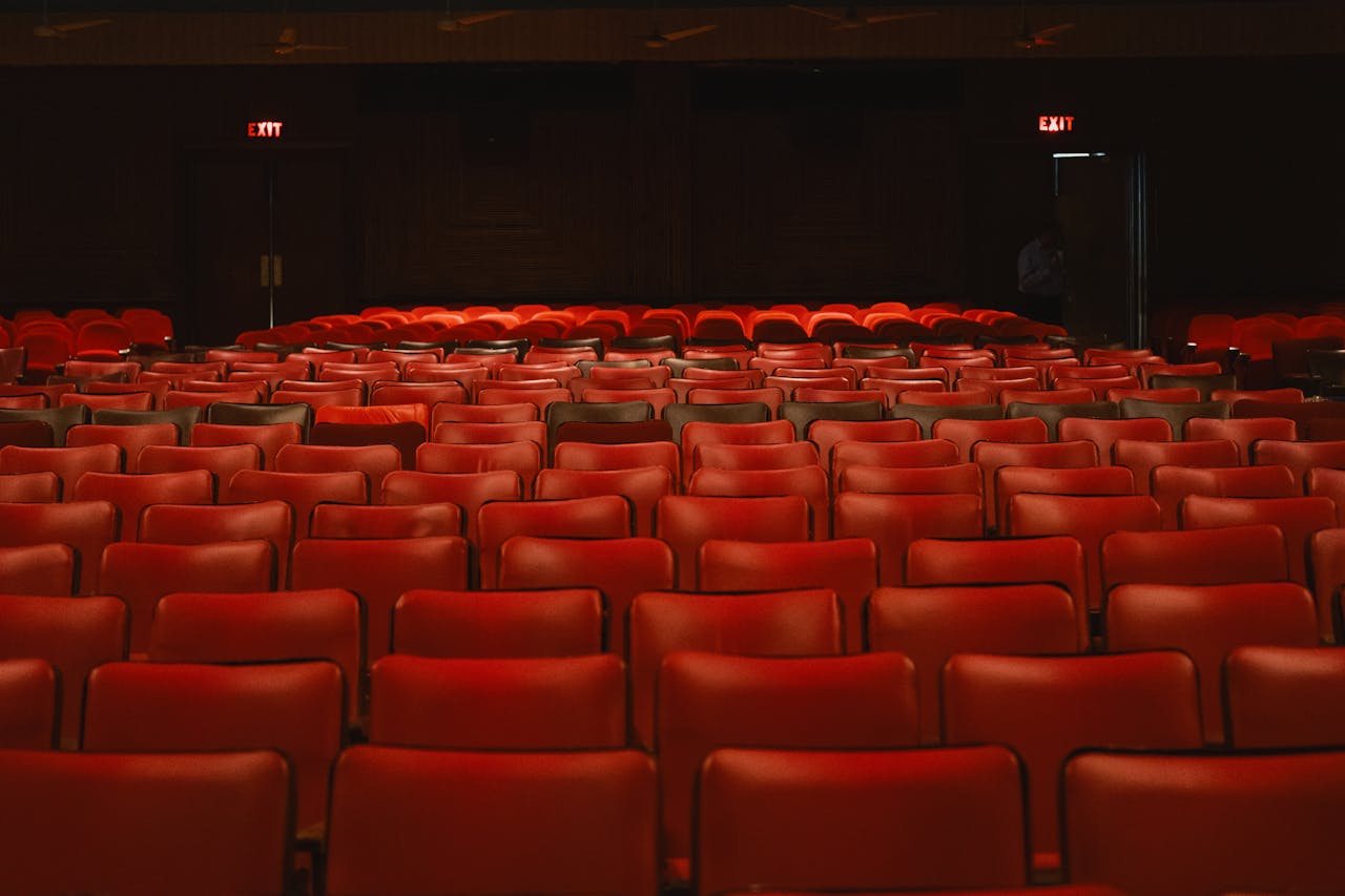 about-us-02 Rows of empty red seats inside a classic movie theater with a vintage ambiance.